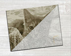 A square canvas art print featuring a sepia-toned kitten peeking from behind a diagonal line of fine line art, displayed on a light gray wood-textured background.